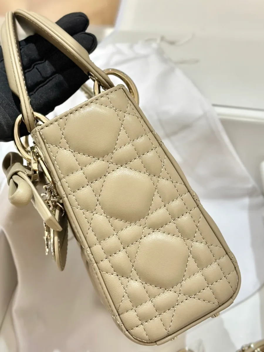 Вид сбоку на бежевую сумку Lady Dior 17 с верхней ручкой и подвеской