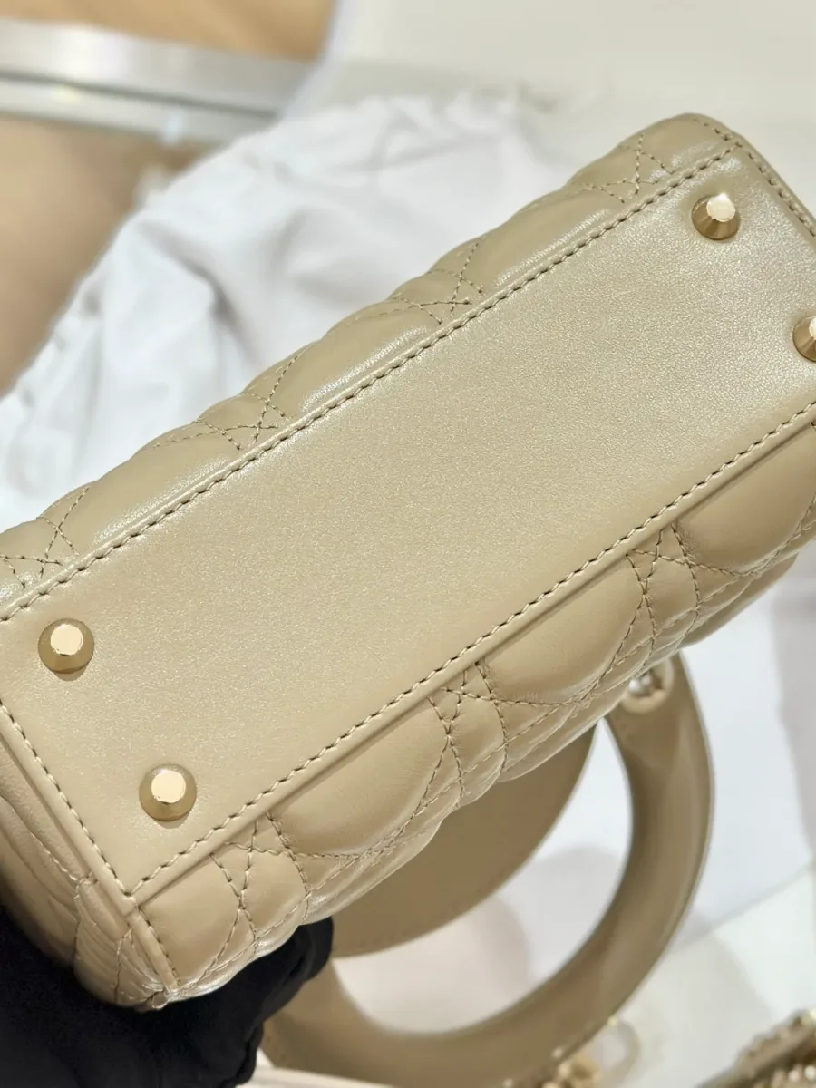 Нижняя часть бежевой сумки Lady Dior 17 с металлическими ножками-заклепками