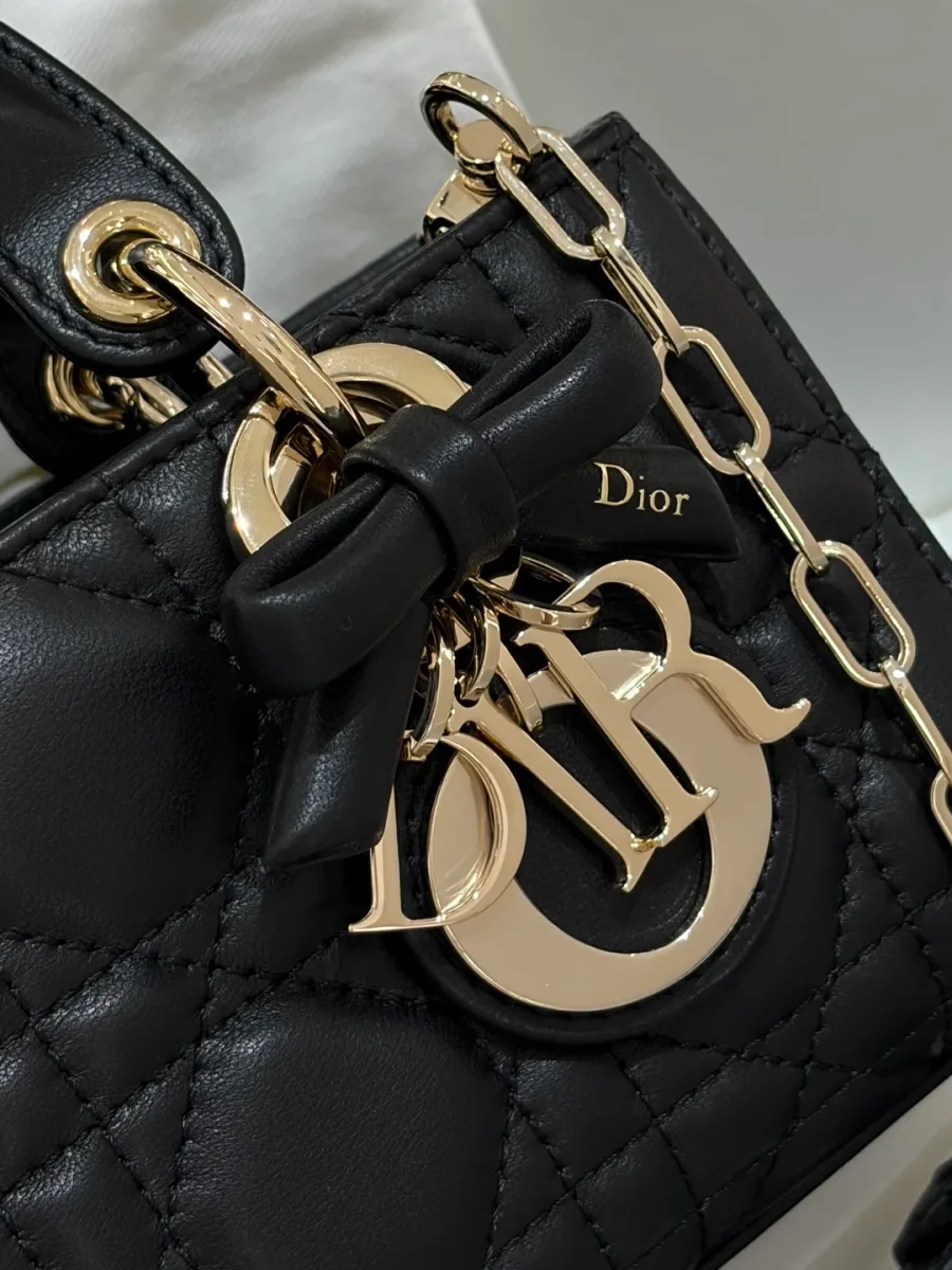 Крупный план золотистых металлических подвесок DIOR и кожаного банта на сумке Dior