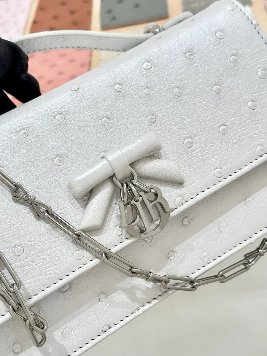 Деталь клатча Dior Jolie WOC: кожаный бант и металлическая подвеска CD с жемчугом