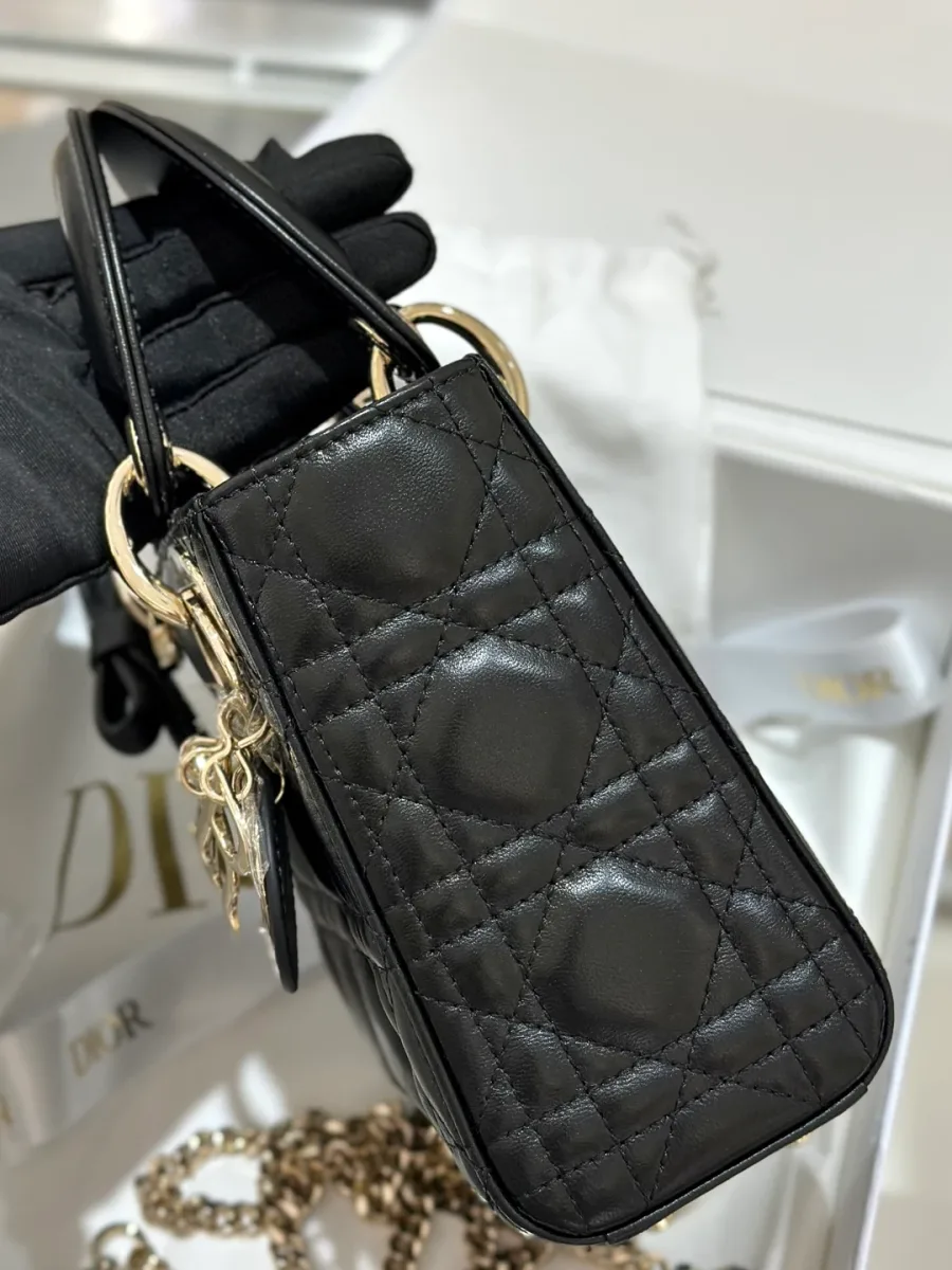 Вид сбоку на черную сумку Lady Dior с золотистыми креплениями ручек