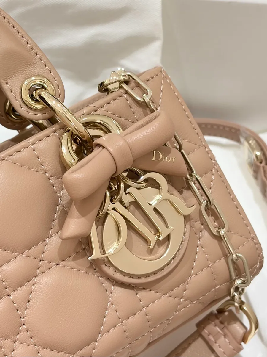 Крупный план золотистой подвески DIOR и декоративного банта на ручке сумки