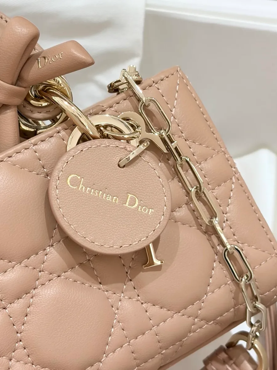 Крупный план круглого кожаного брелока Christian Dior на бежевой стеганой сумке