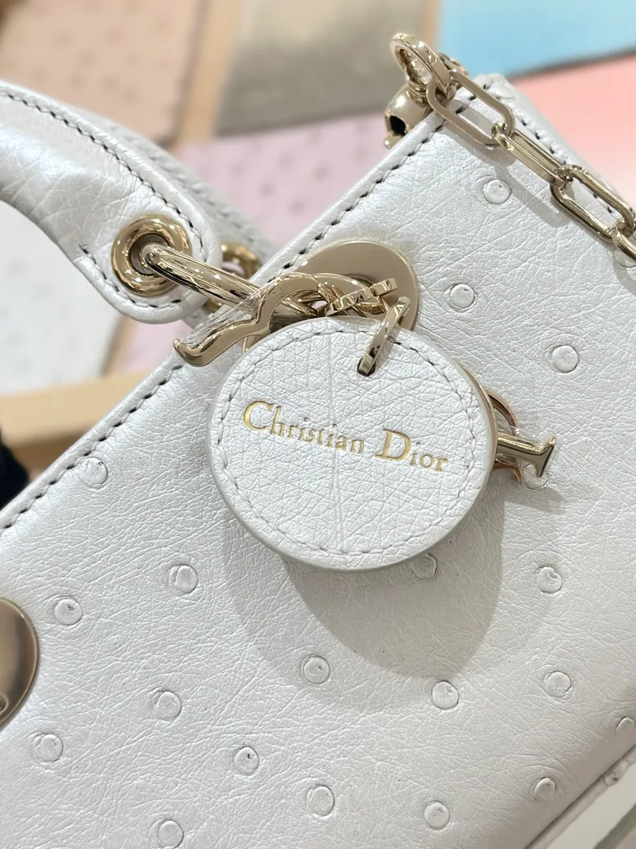 Крупный план кожаного брелока с тиснением Christian Dior на белой сумке