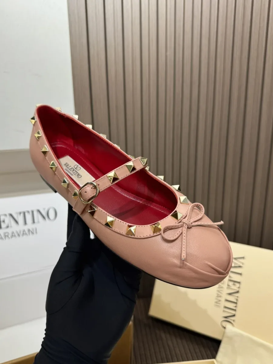 Розовая балетка с шипами Rockstud и ремешком в руке, общий план