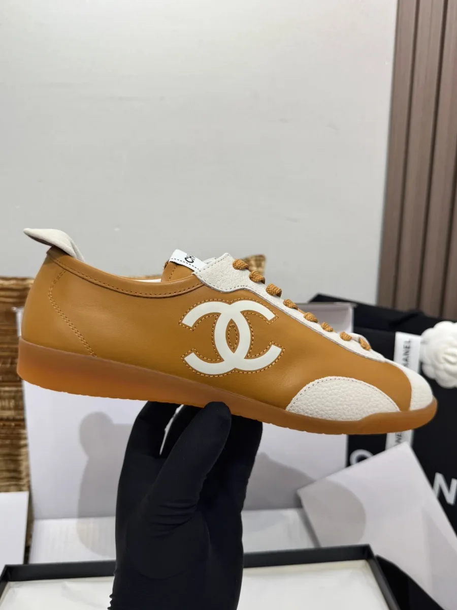 Коричневый кед с белым логотипом CC в руке, вид сбоку