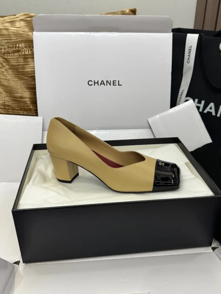 Один бежевый туфель Chanel с чёрным лакированным носком, профиль в обувной коробке