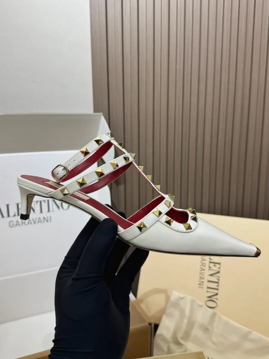 Белая туфля Rockstud на низком каблуке в руке, вид сбоку