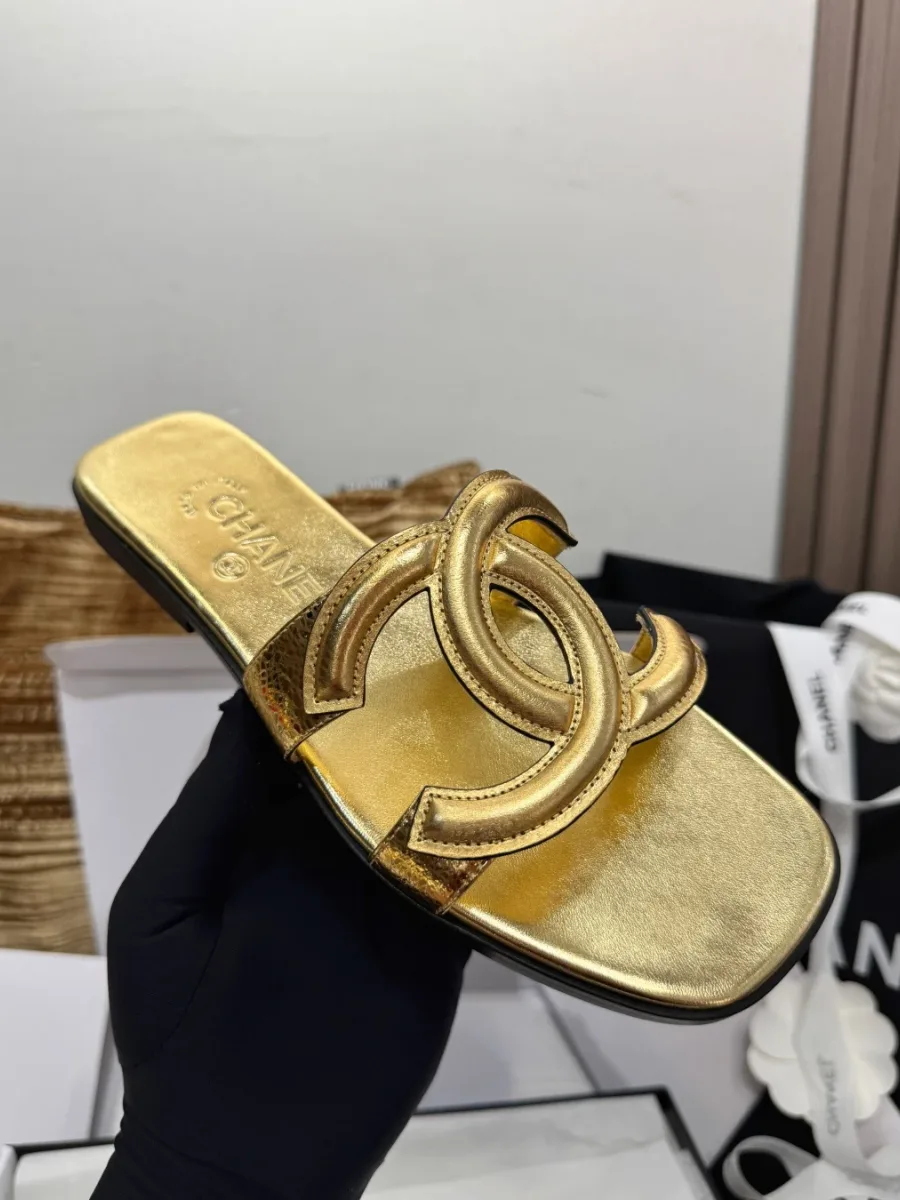 Золотистый шлёпанец Chanel с перемычкой CC, вид сверху в руке