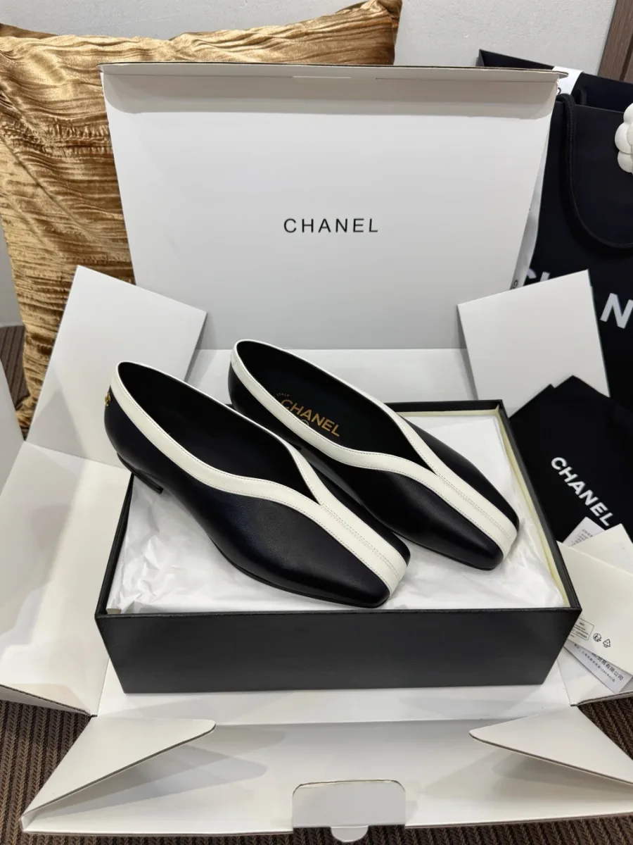 Пара чёрно-белых туфель Chanel в открытой коробке, ракурс сверху