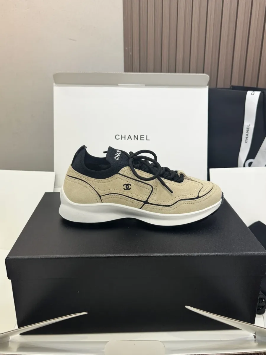 Боковой профиль бежевого кроссовка Chanel с чёрным кантом и логотипом CC