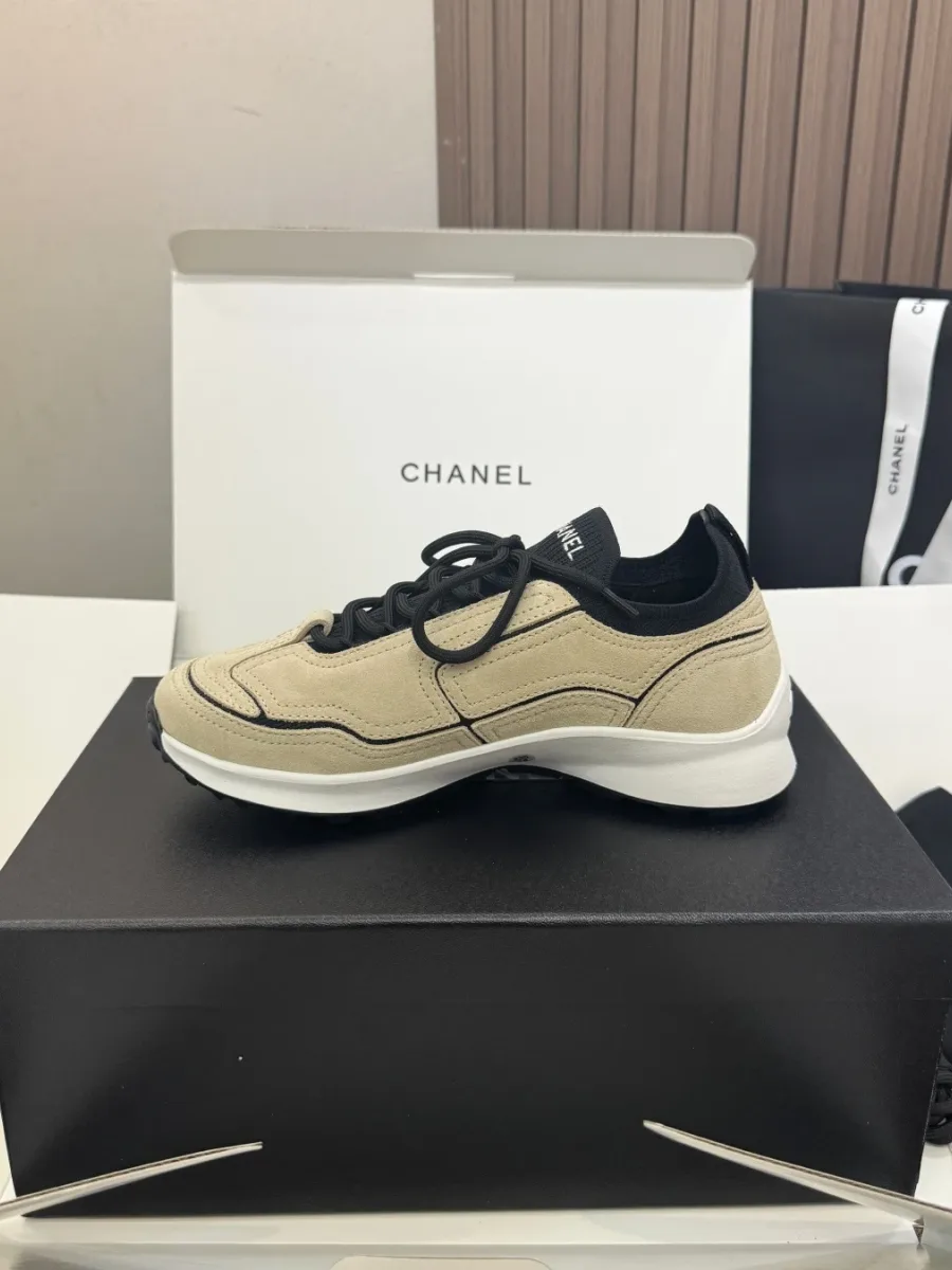 Внутренняя боковая сторона бежевого кроссовка Chanel на чёрной коробке