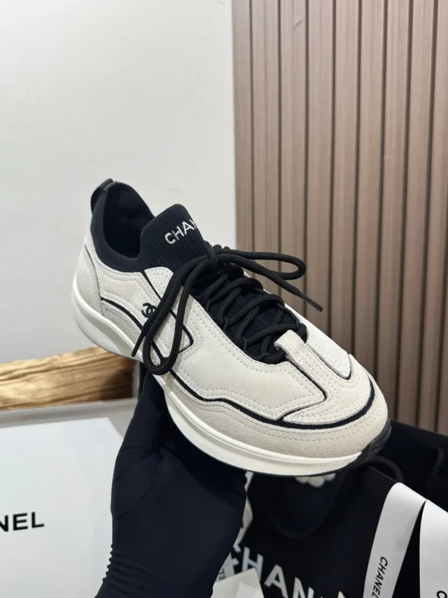 Кроссовок Chanel в руке, ракурс три четверти спереди с черной шнуровкой