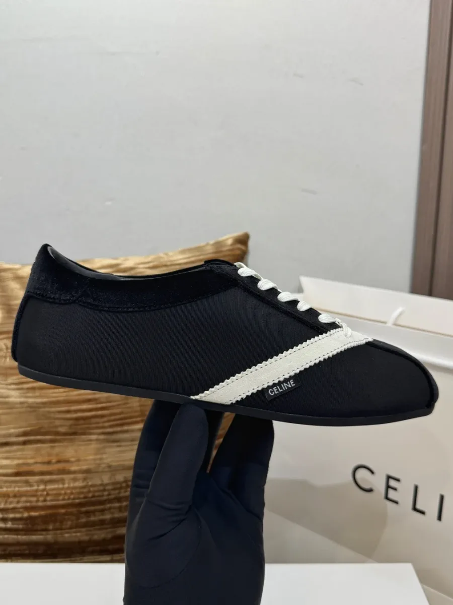 Чёрный кед The Flat в руке в перчатке, вид сбоку