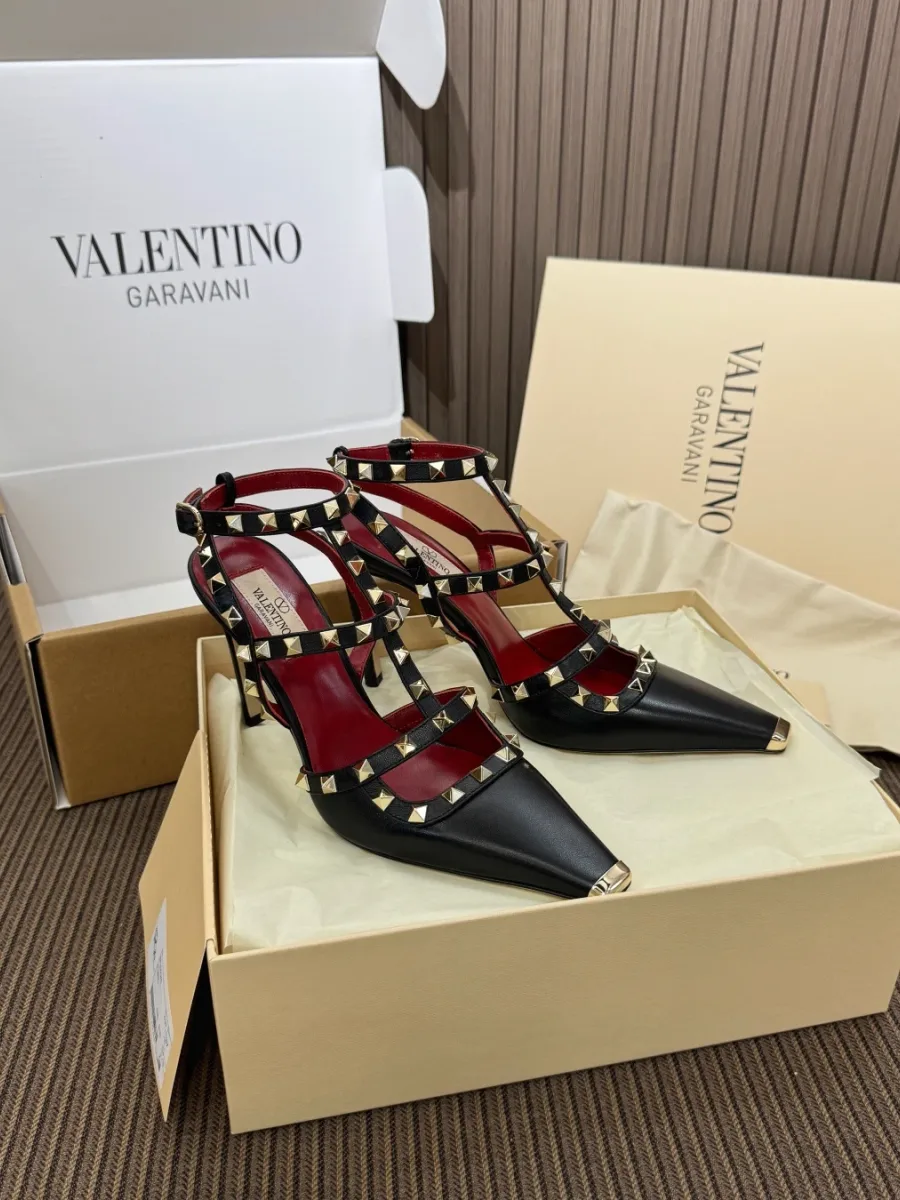 Пара чёрных туфель на каблуке с шипами Rockstud в коробке, ракурс три четверти спереди
