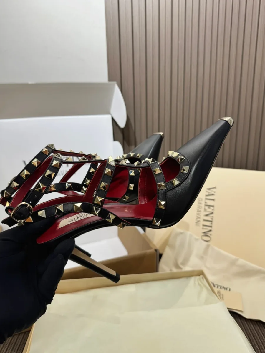 Чёрная туфля Rockstud в руке, боковой ракурс с акцентом на ремешки и каблук