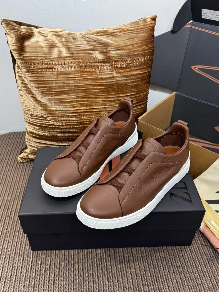 Мужские кожаные кеды Zegna коньячного цвета на коробке, вид под углом сбоку
