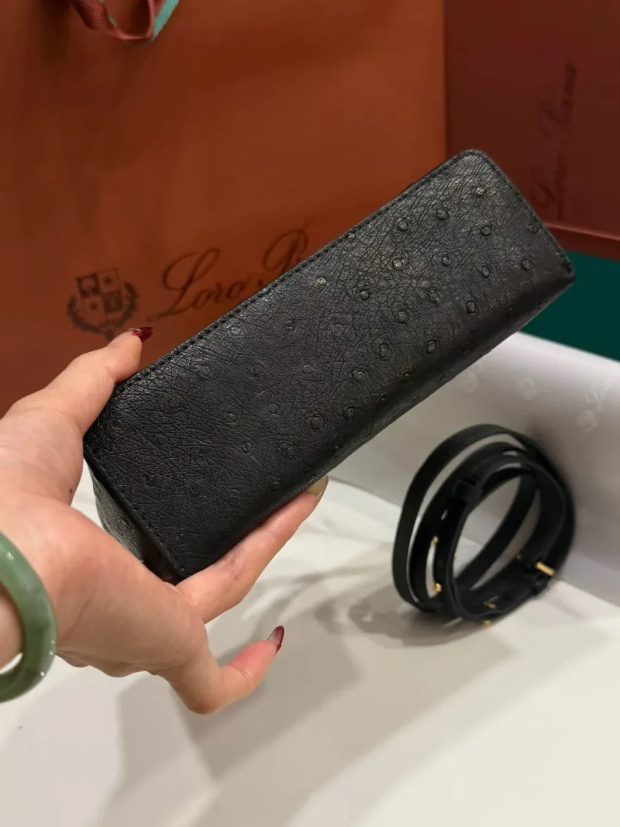 Нижняя часть и плоское дно чёрной сумки из кожи страуса в руке