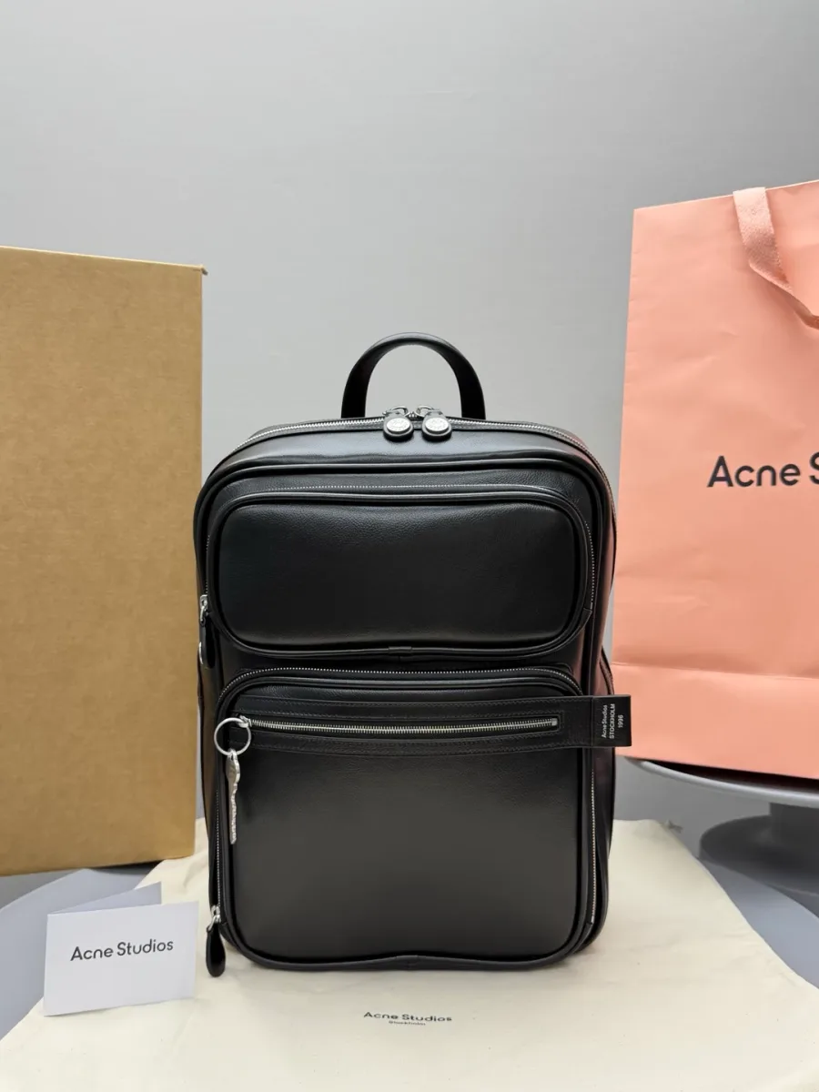 Чёрный кожаный рюкзак Acne Studios, фронтальный ракурс на фоне фирменной упаковки