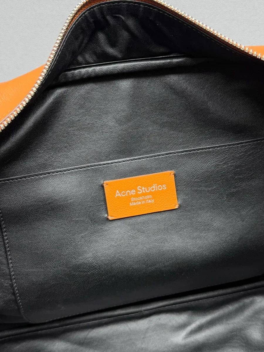 Крупный план внутреннего кармана с оранжевой кожаной нашивкой Acne Studios