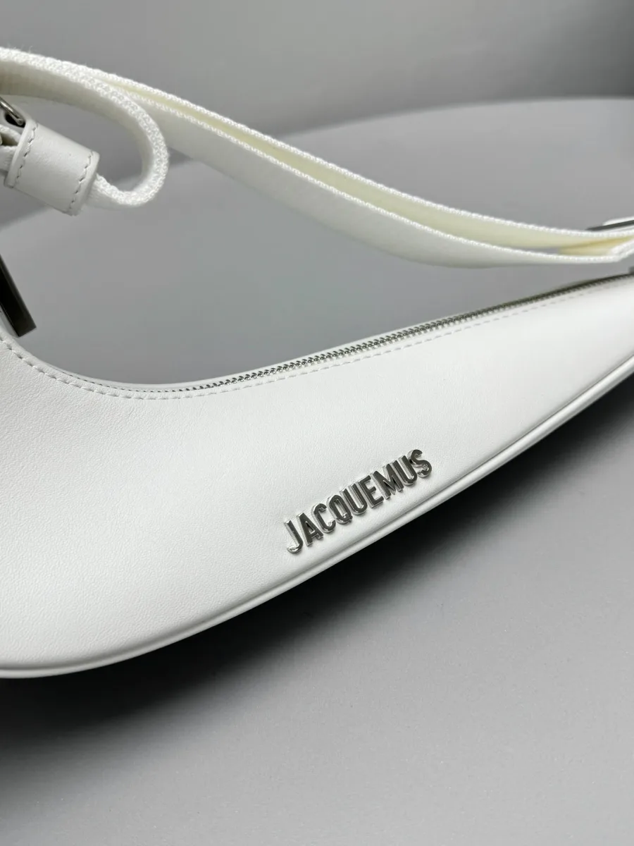 Крупный план корпуса белой сумки с металлическим логотипом Jacquemus и молнией