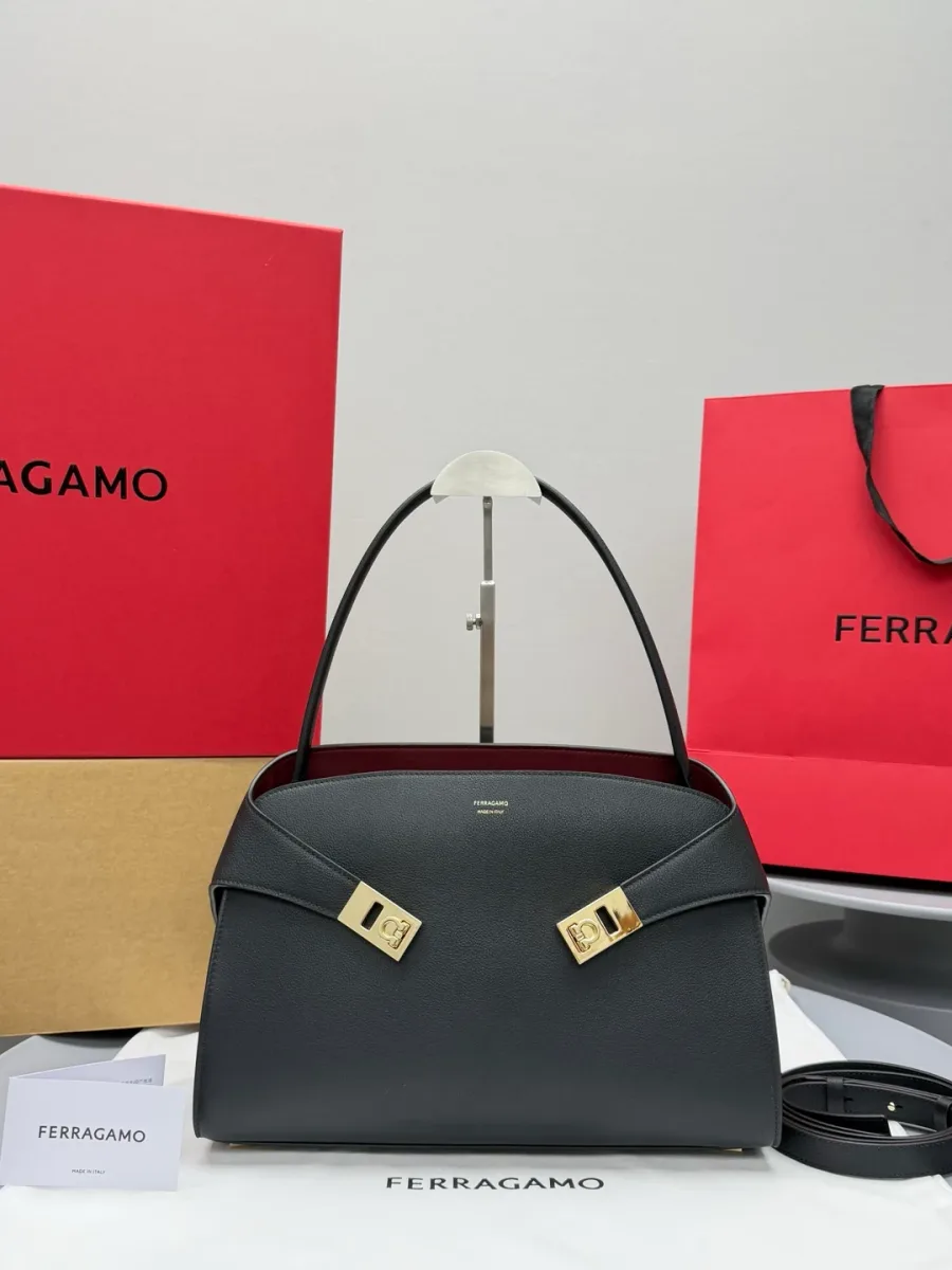 Чёрная кожаная сумка Hug Soft с длинным ремнем на фоне фирменной упаковки Ferragamo