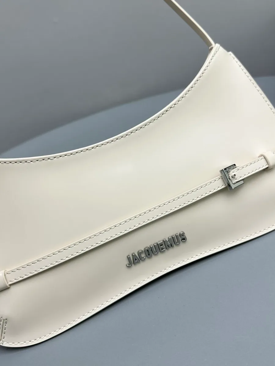 Крупный план низа сумки с металлическим логотипом Jacquemus и пряжкой