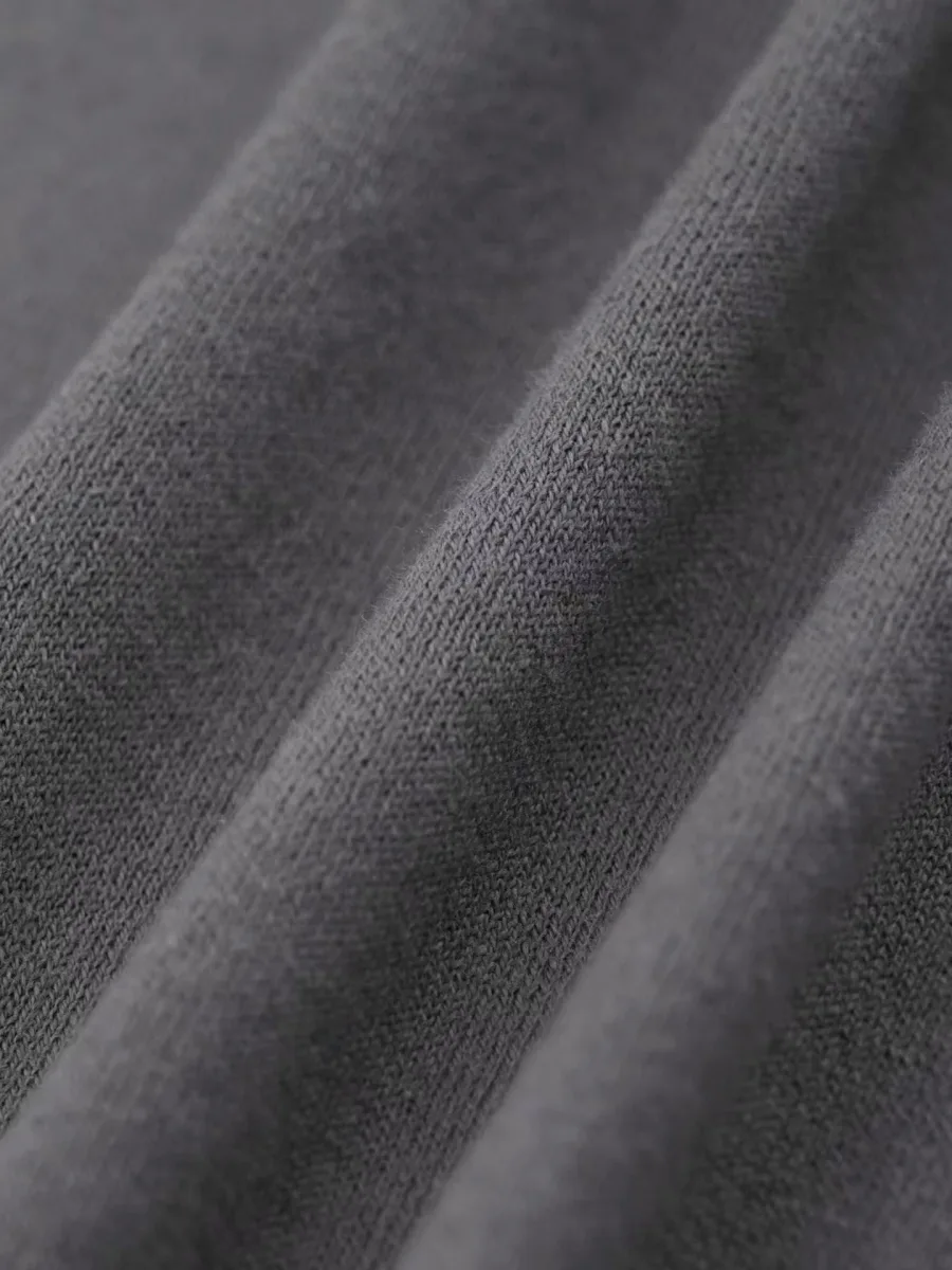 Серая футболка на модели в ракурсе спереди, видны короткий рукав и красная вышивка на груди