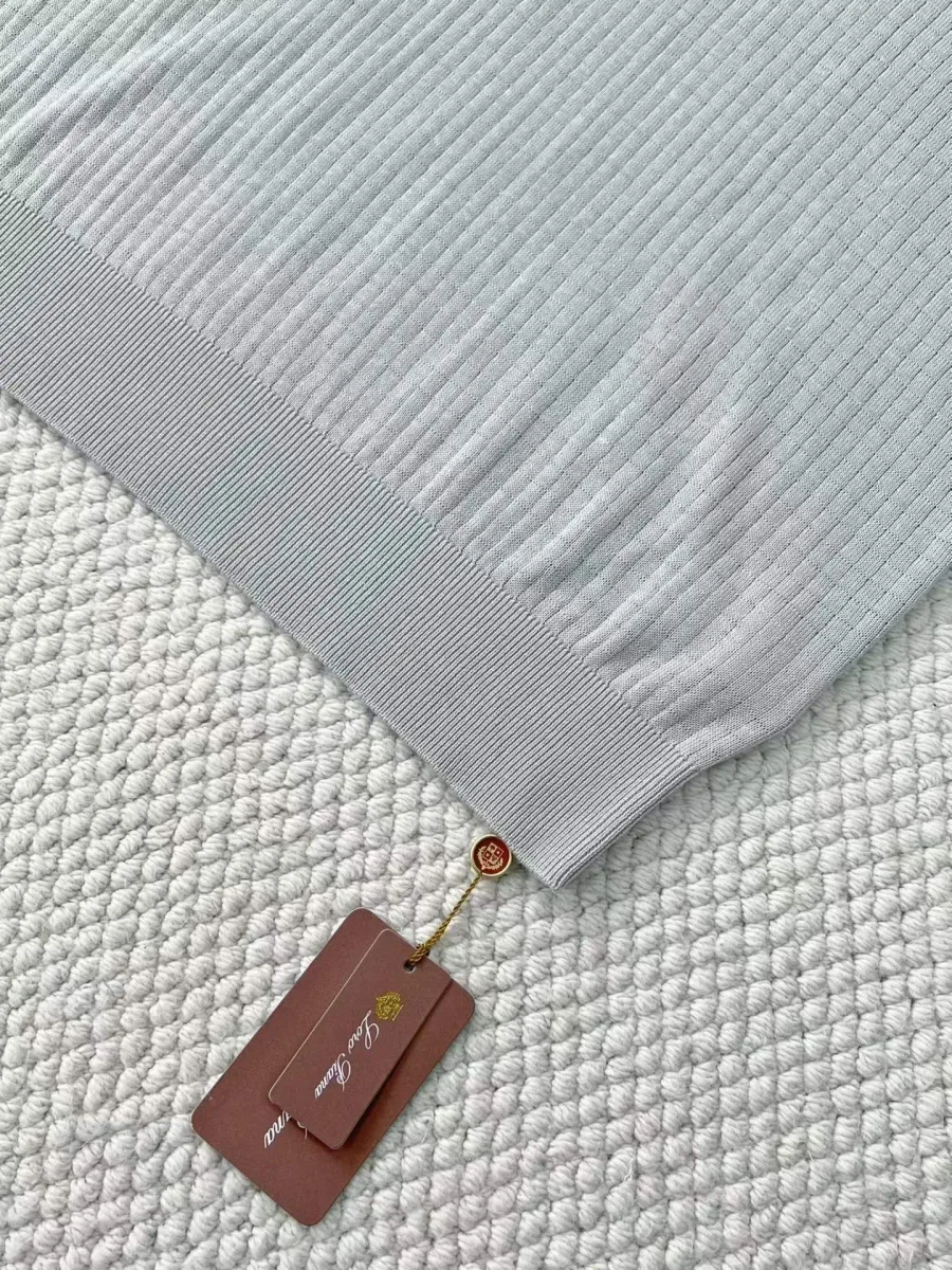 Фрагмент серого мужского поло Loro Piana с фактурной вязкой, нижней резинкой и биркой
