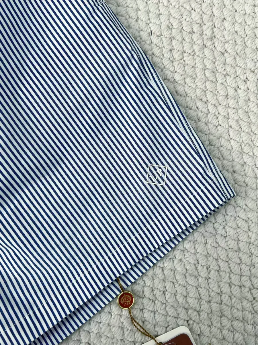 Фрагмент плавательных шорт с диагональной полоской, вышитой эмблемой и закруглённым низом