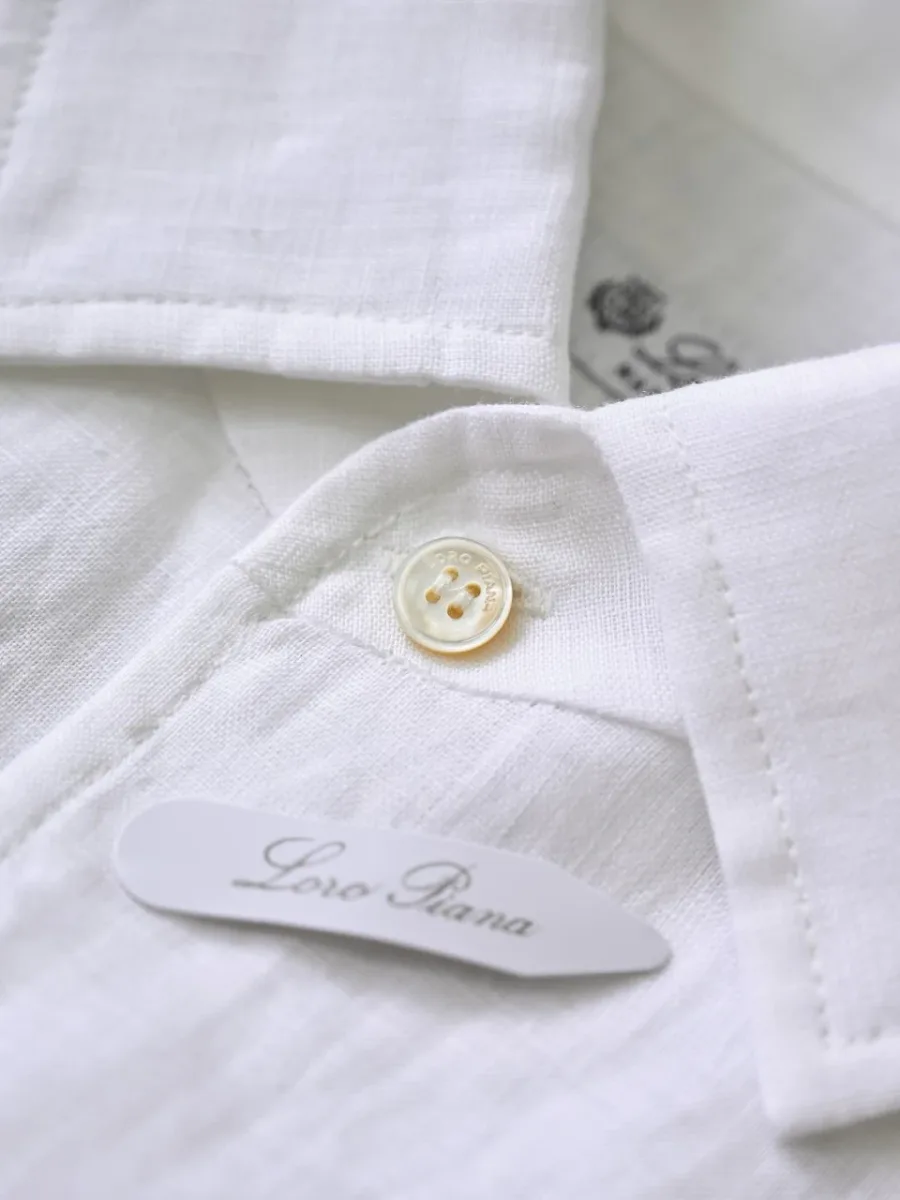 Белая льняная рубашка Loro Piana крупным планом с фактурой льна и нижней планкой с пуговицами