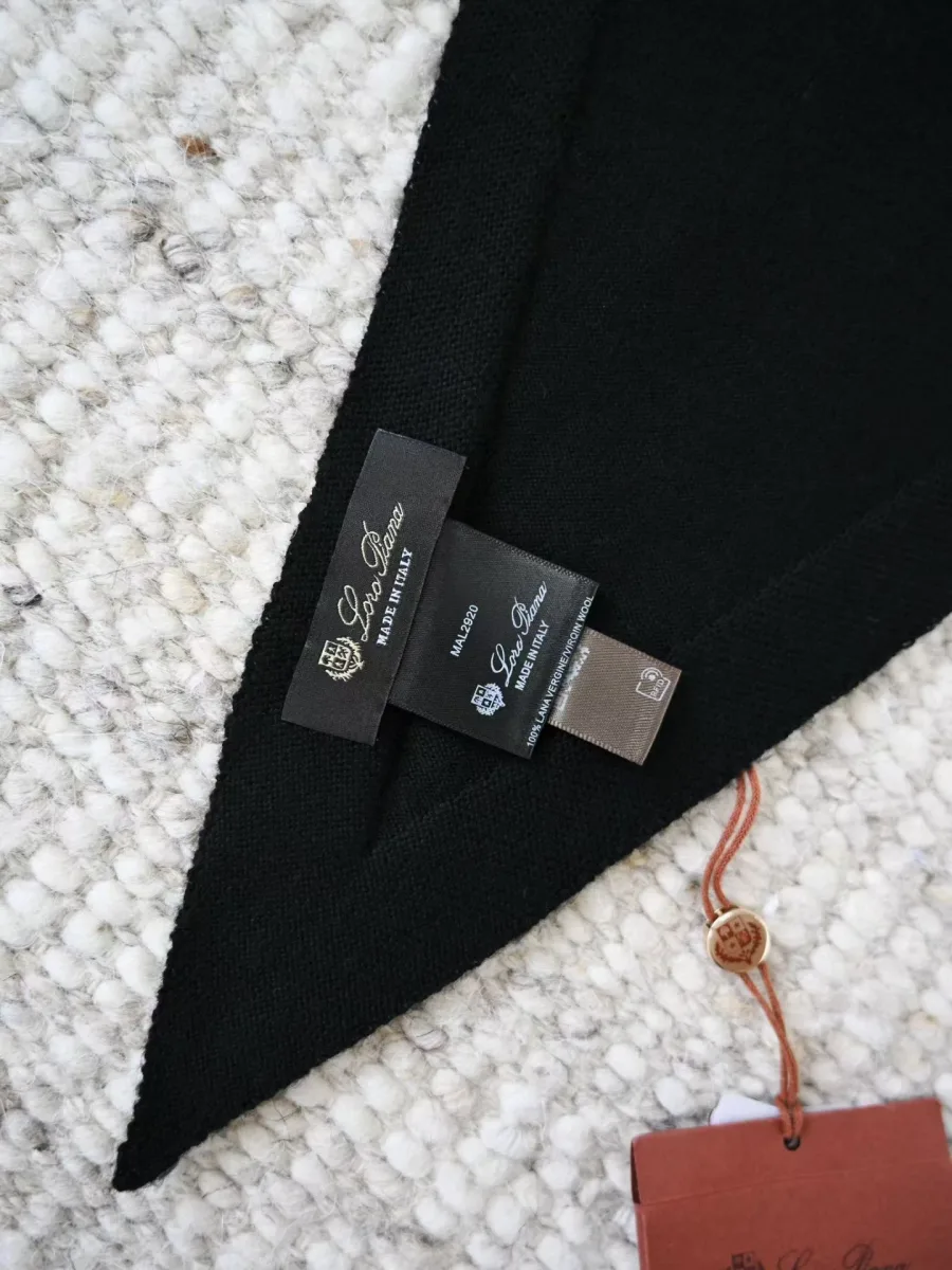 Край чёрного шарфа Loro Piana с несколькими бирками и декоративным подвесом
