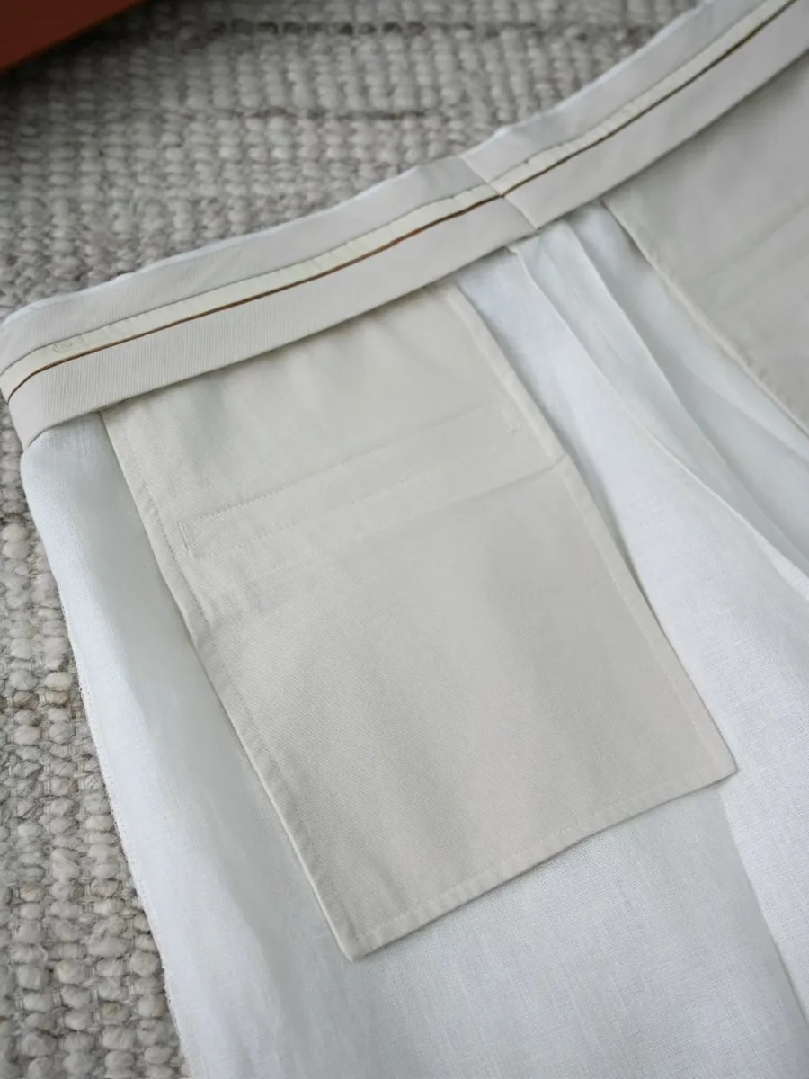 Белые льняные шорты крупным планом, вид бокового кармана и складок на передней части