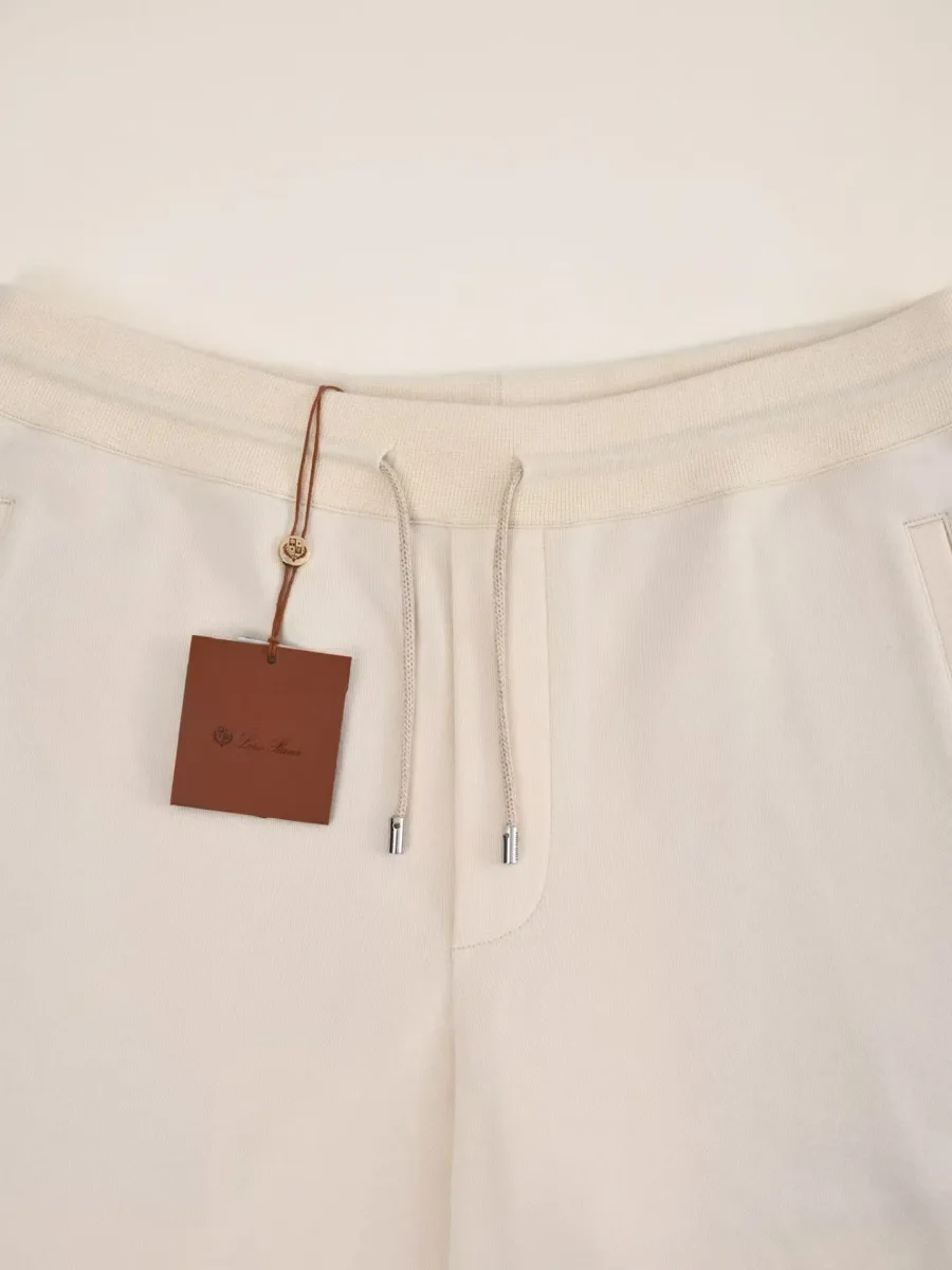 Молочные шорты Loro Piana крупным планом: пояс, шнурок с металлическими наконечниками и бирка