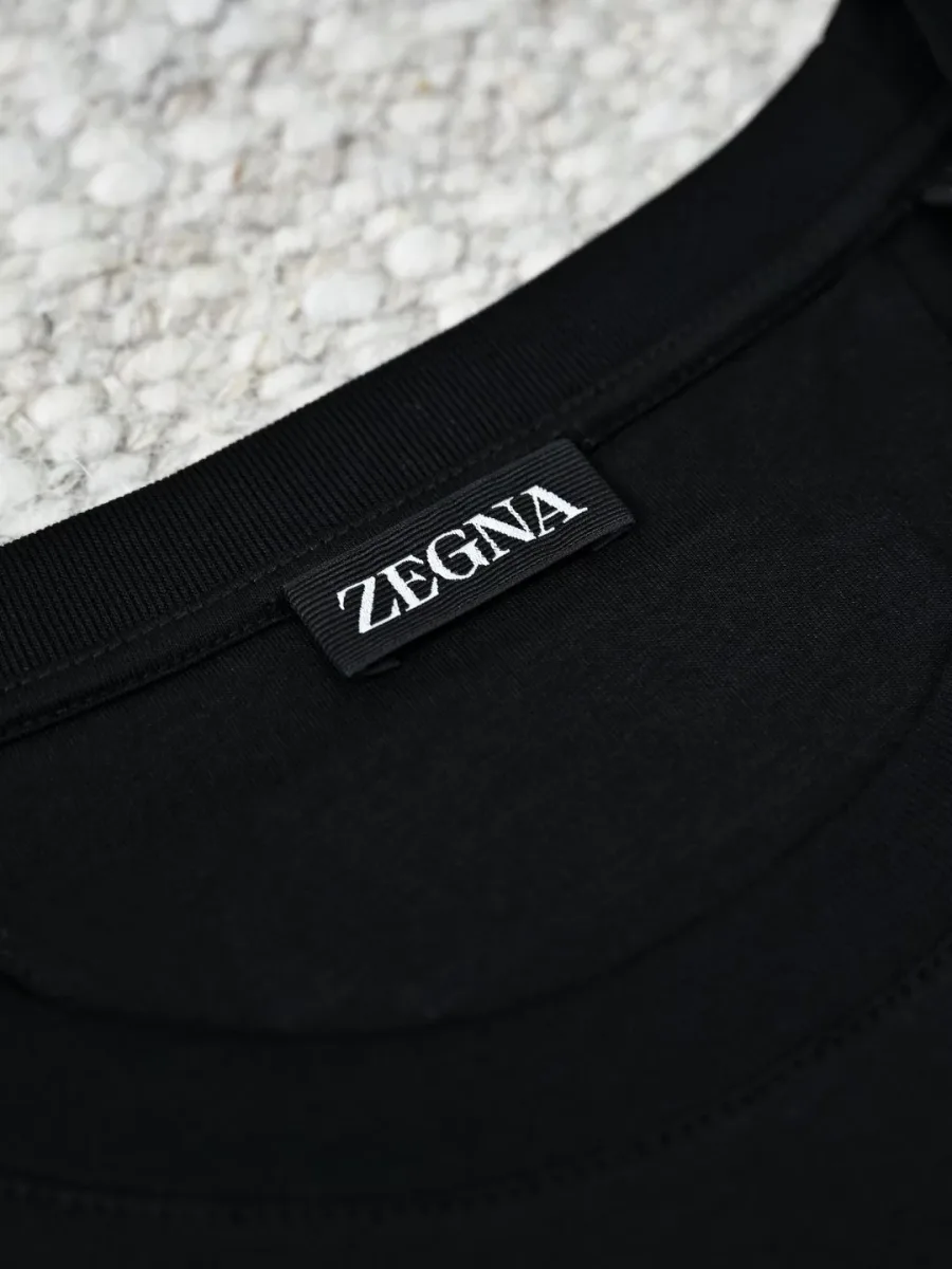 Чёрная футболка Zegna крупным планом, видны ребристая окантовка горловины и фирменная бирка