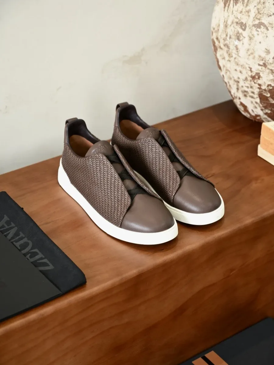 Пара коричневых кроссовок Zegna в ракурсе сверху, белая резиновая подошва и плетёный текстиль
