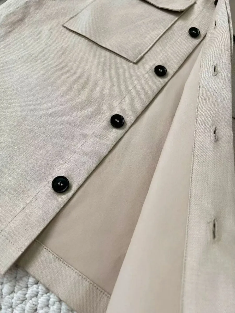 Фрагмент светло-бежевой рубашки Zegna с отложным воротником и чёрными пуговицами