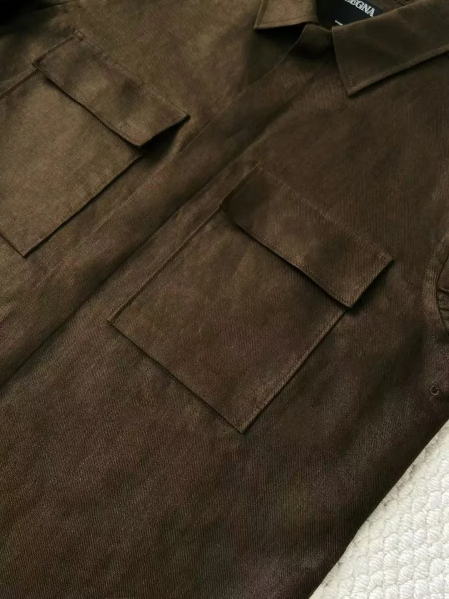 Фрагмент тёмно-коричневой рубашки Zegna с нагрудным карманом, планкой и контрастной пуговицей