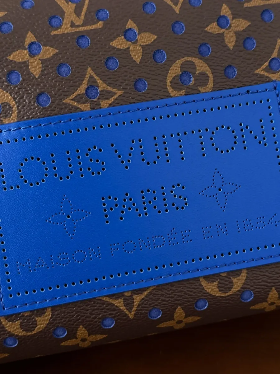 Крупный план синего кожаного патча с тиснением Louis Vuitton Paris на сумке
