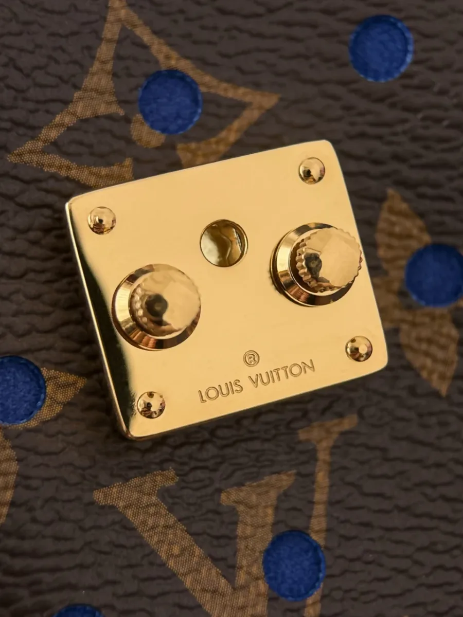 Крупный план золотистого замка-защелки с гравировкой Louis Vuitton