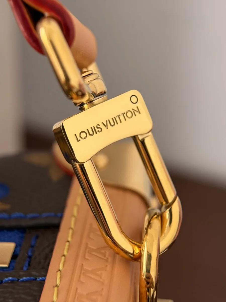 Крупный план золотистого карабина с гравировкой Louis Vuitton