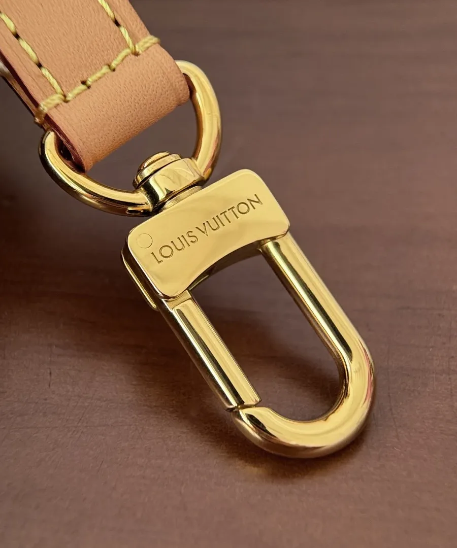 Крупный план золотистого карабина с гравировкой Louis Vuitton