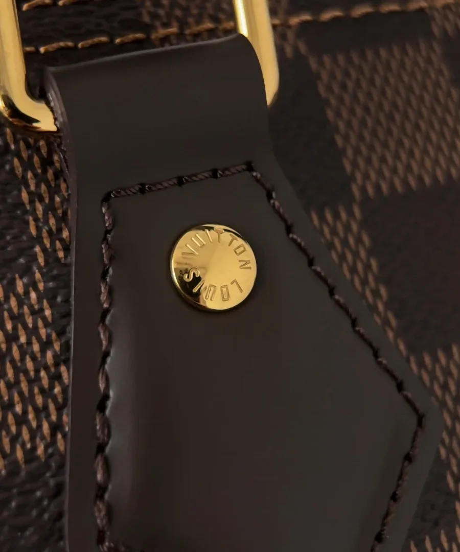 Крупный план кожаного крепления ручки с золотистой заклепкой Louis Vuitton