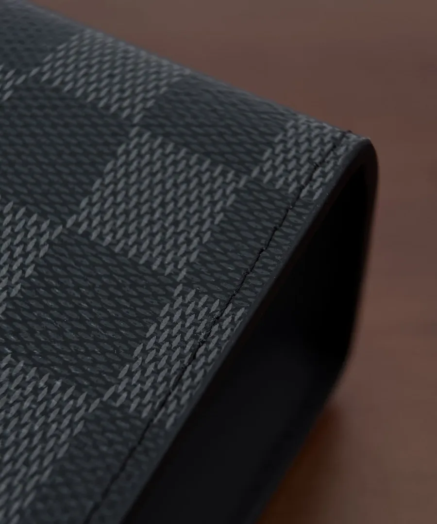 Крупный план угла и текстуры канвы Damier Graphite черного клатча