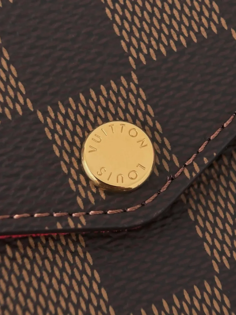 Кнопка-застежка золотистого цвета с гравировкой Louis Vuitton на клапане сумки