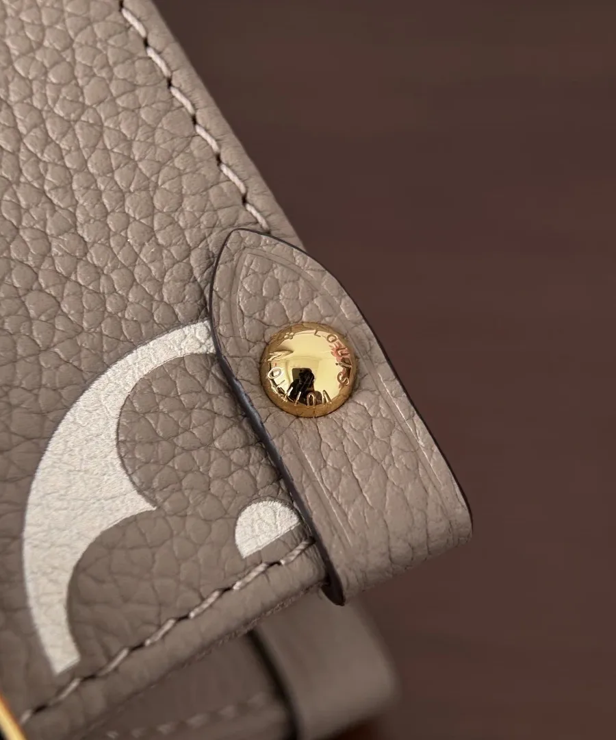 Золотистая кнопка-заклепка с гравировкой Louis Vuitton на боковой части сумки