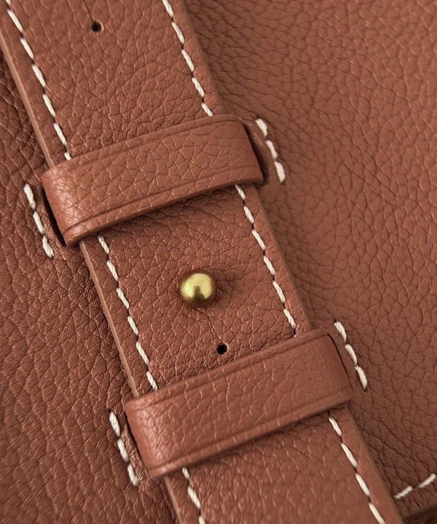Крупный план регулируемого ремешка коричневой сумки Louis Vuitton с белой прострочкой
