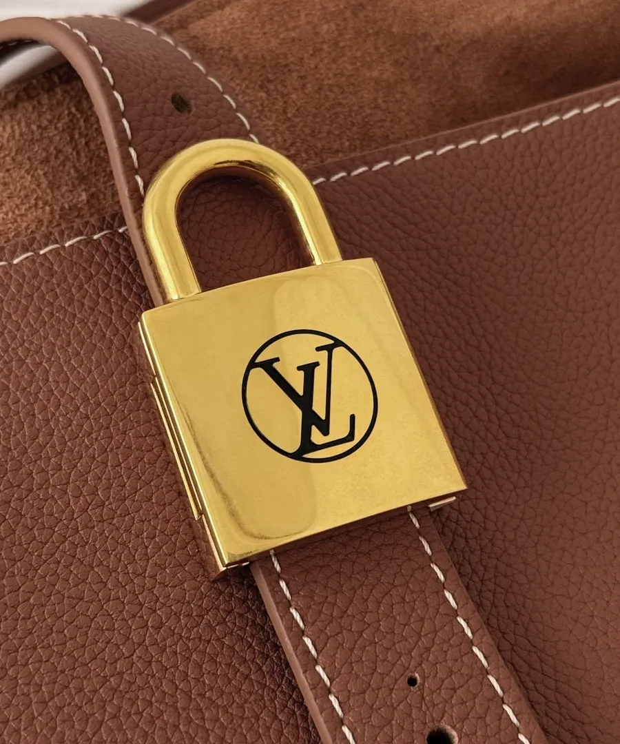 Золотистый замок-падлок с логотипом LV на ремешке коричневой сумки Louis Vuitton