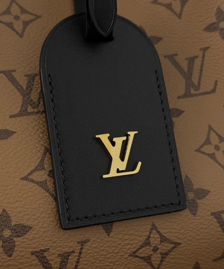 Крупный план черной кожаной бирки с золотистым логотипом LV на сумке.