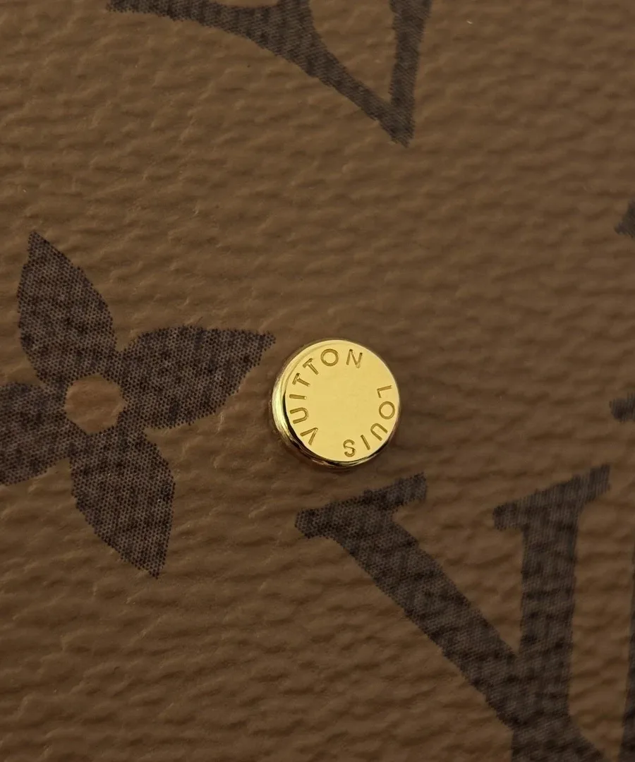 Золотистая металлическая кнопка с гравировкой Louis Vuitton на сумке.